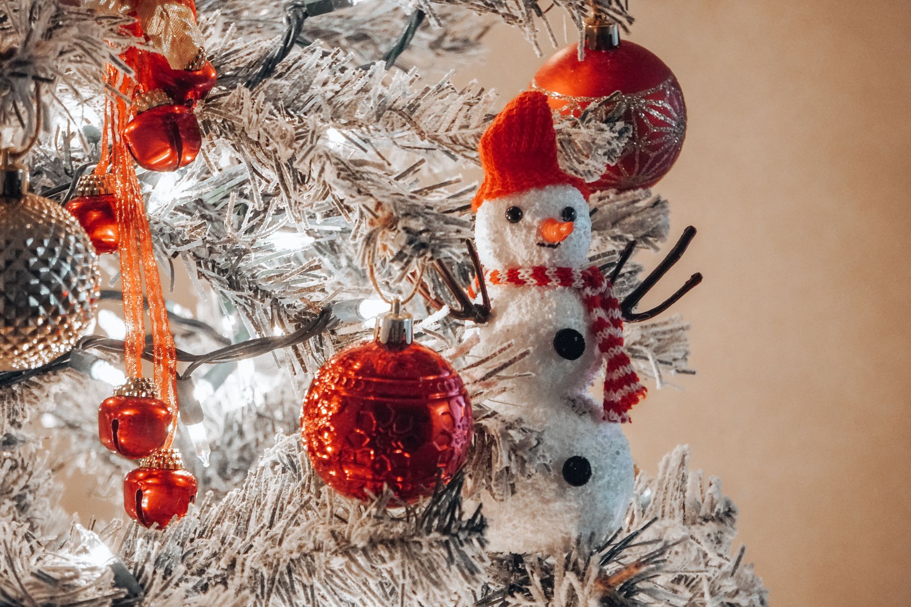 home depot christmas decorations sale A close-up of a Christmas tree with red ornaments and a snowman decoration, evoking holiday cheer.