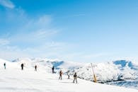 滑雪者在阳光明媚的一天，于风景如画的雪山中享受冬季运动，非常适合爱好者