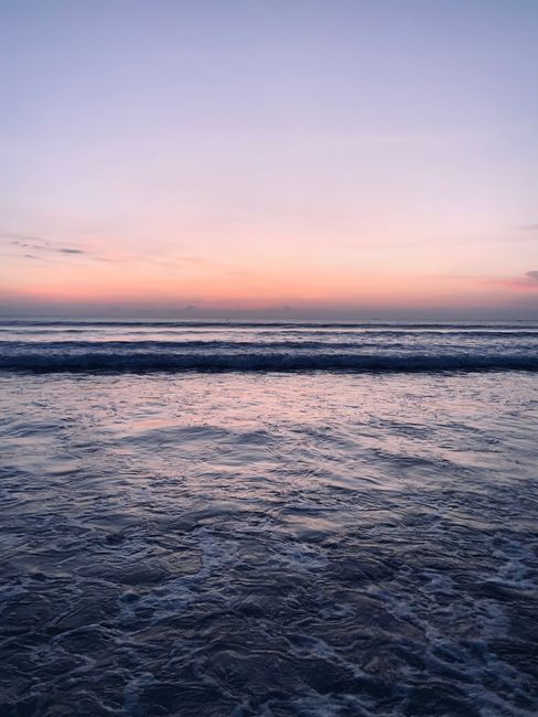 A serene view of ocean waves under a pink and purple sunset sky, perfect for relaxation themes.