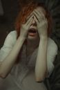 Scared woman covering eyes with hands