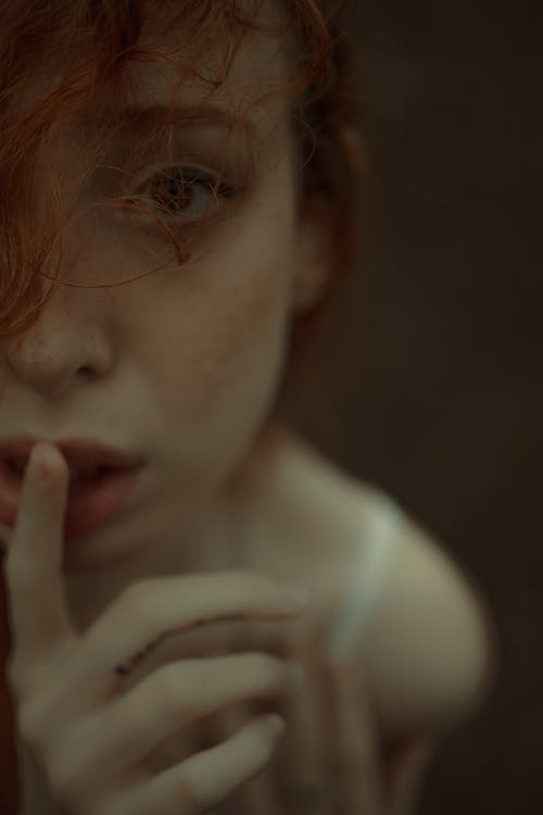 Tender redhead woman with finger on lips