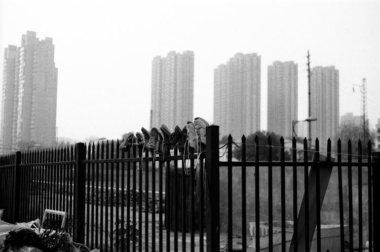 Shoes Drying On Fence In City