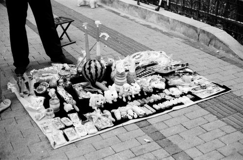 Free Black and white photo of toys sold on a blanket by a street vendor in urban market. Stock Photo