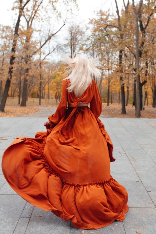 A woman in an orange dress is walking through a park Free Stock Photo A woman in an orange dress is walking through a park Free Stock Photo