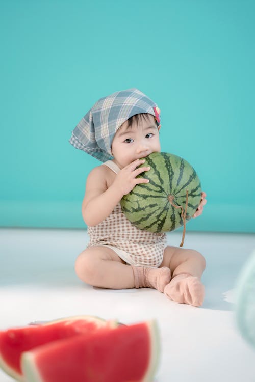 Baby Girl Sitting and Biting Watermelon