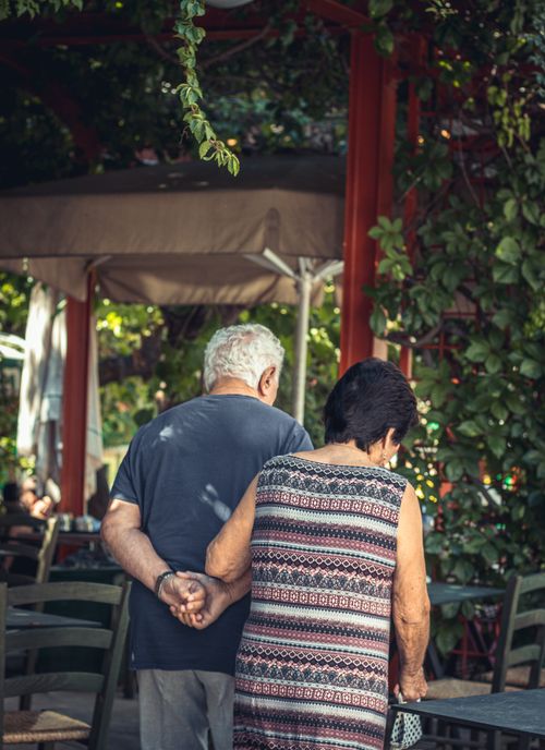 Free Charming scene of an elderly couple walking together in a lush garden restaurant. Heartwarming moment in serene outdoor setting. Stock Photo