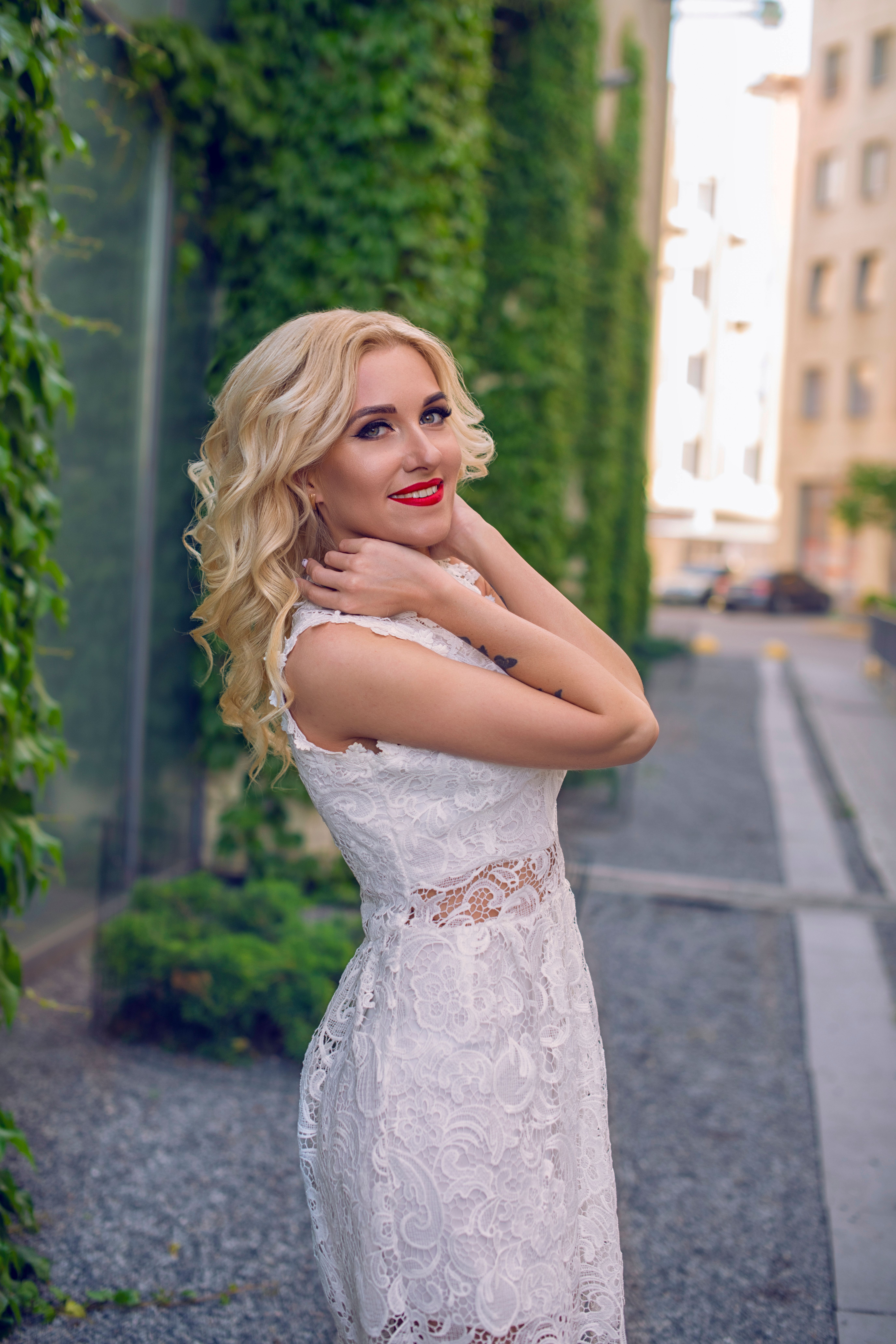 Elegant bride in a lace dress posing on a vibrant London street on a sunny day.