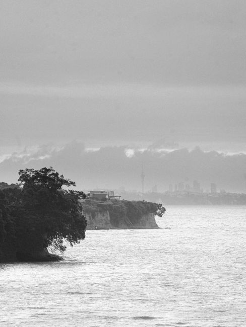 Black and white photo of a coastal cityscape with dramatic clouds and waterfront.