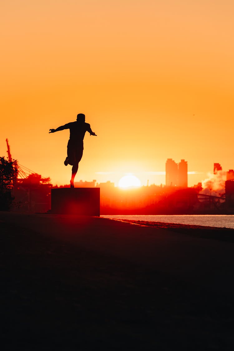 Silhouette Of A Man Jumping Outside At Sunrise