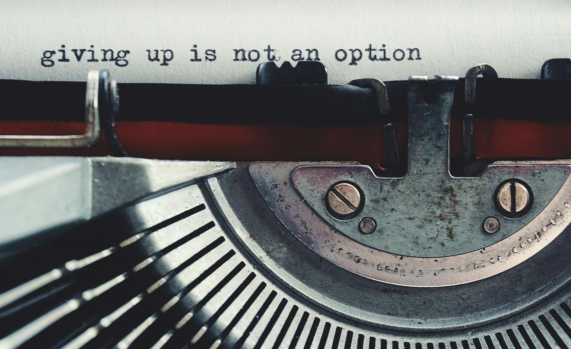 Close-up of a vintage typewriter typing 'giving up is not an option.'
