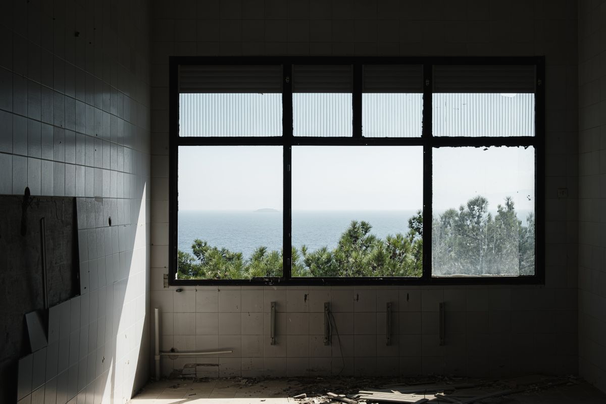 An empty room with large windows providing a serene ocean view, capturing tranquility.