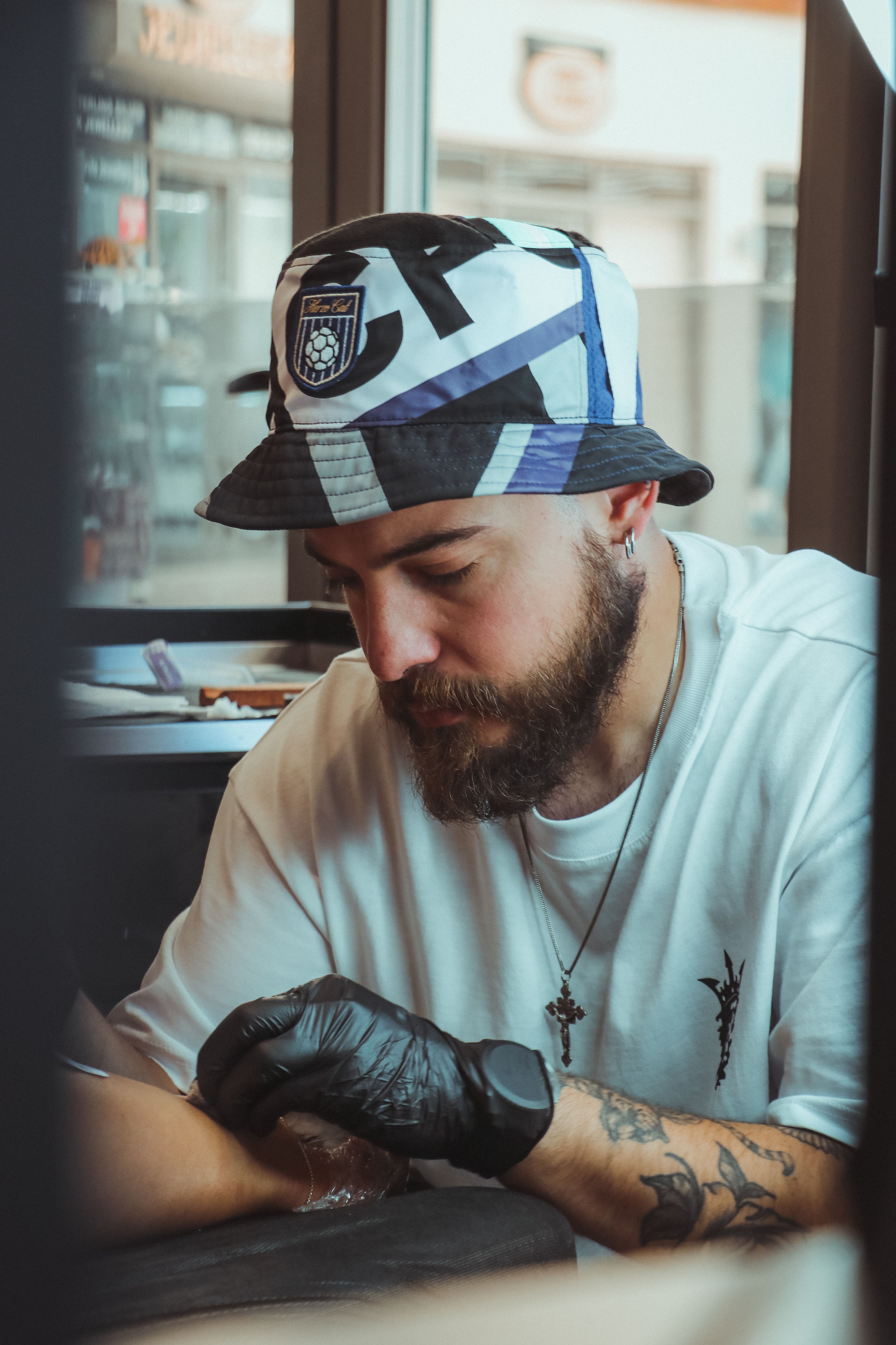 Tattoo artist in Aydın, Türkiye focuses intensely while applying intricate ink design.