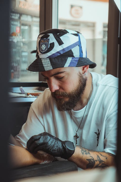 Free A man with tattoos and a hat is sitting at a table Stock Photo