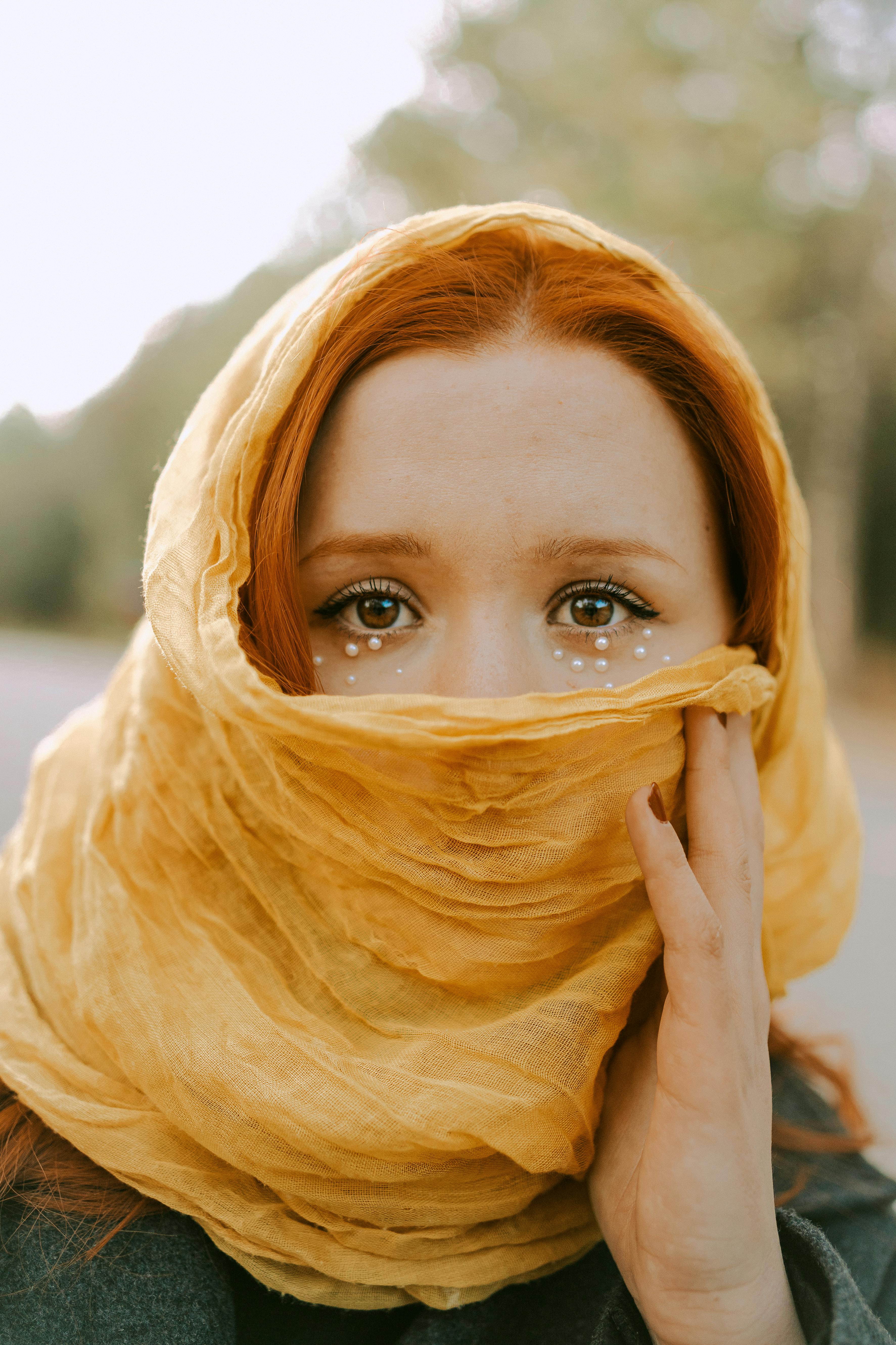 a woman with red hair and yellow scarf covering her face