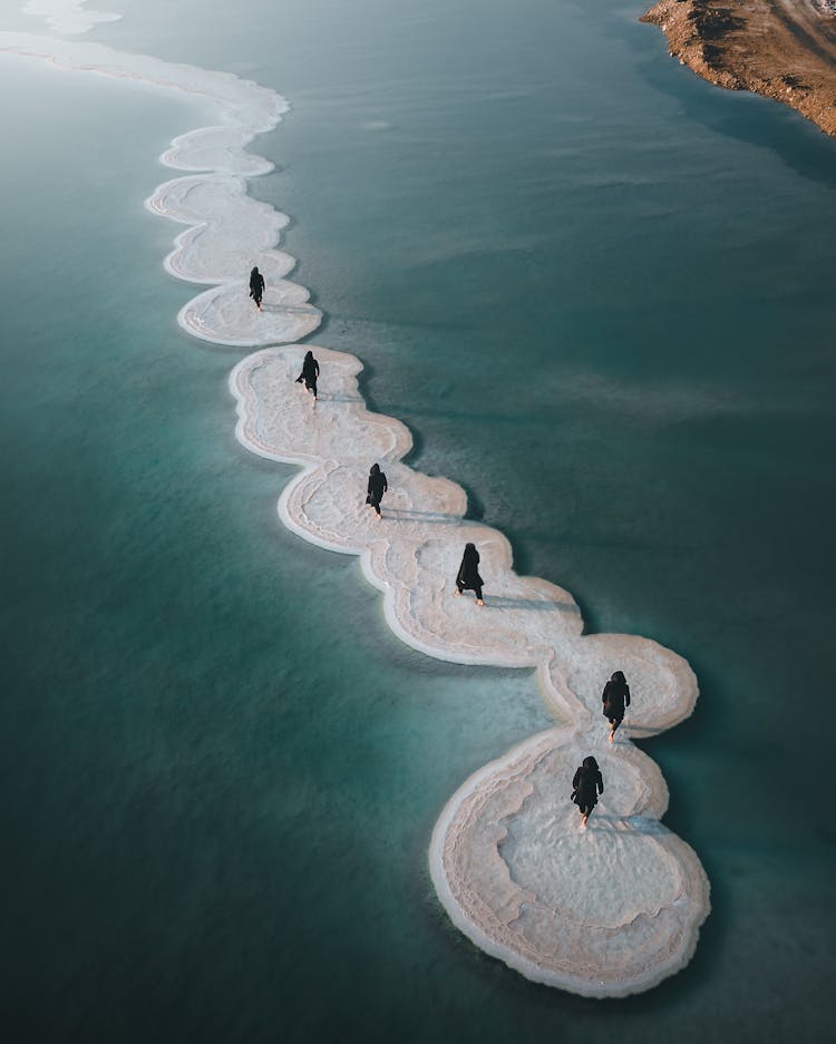 People In Black Hooded Clothes On Salt Formations In Dead Sea Lake