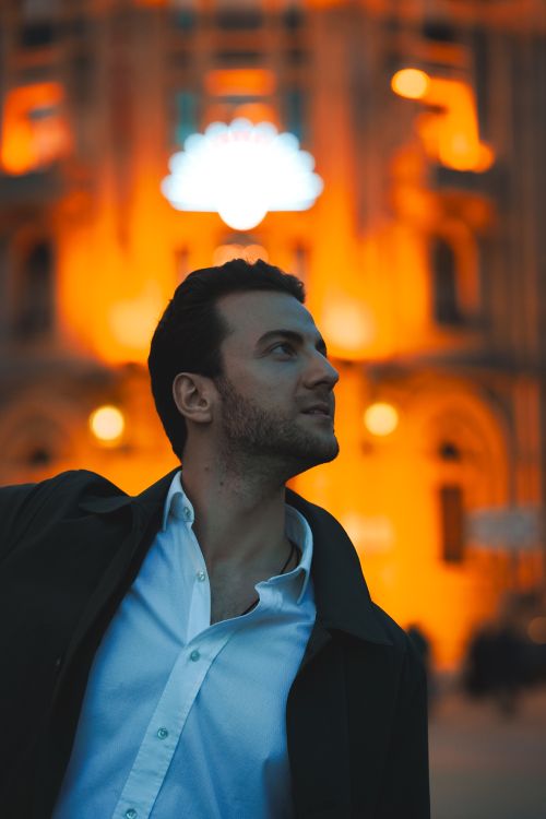 Free Charming portrait of a man in a suit jacket with a vibrant night city background. Stock Photo