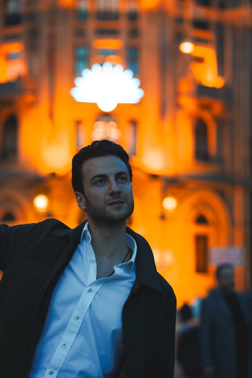 Free Portrait of a stylish man in front of illuminated architecture in Ankara at sunset. Stock Photo