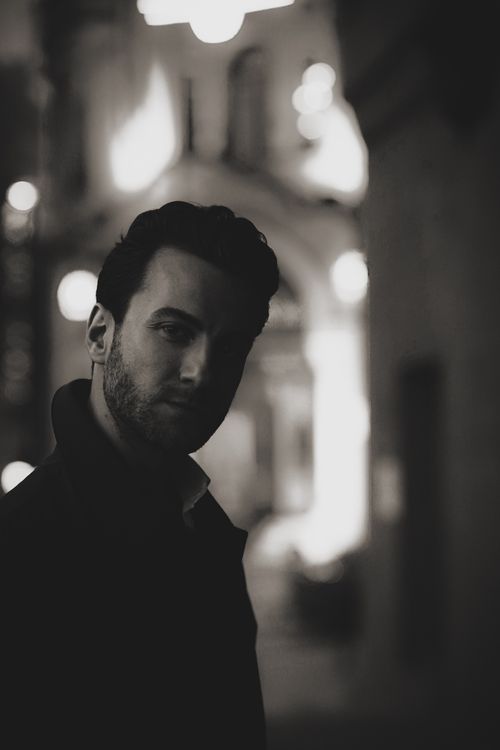 Free A moody black and white portrait of a man standing in an illuminated city street at night in Ankara. Stock Photo
