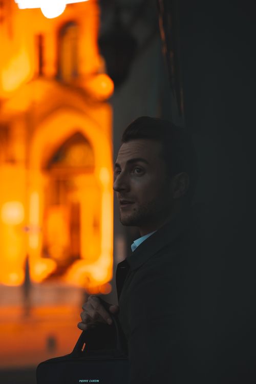 Free Portrait of a man standing against a warmly lit urban backdrop in Ankara at sunset. Stock Photo