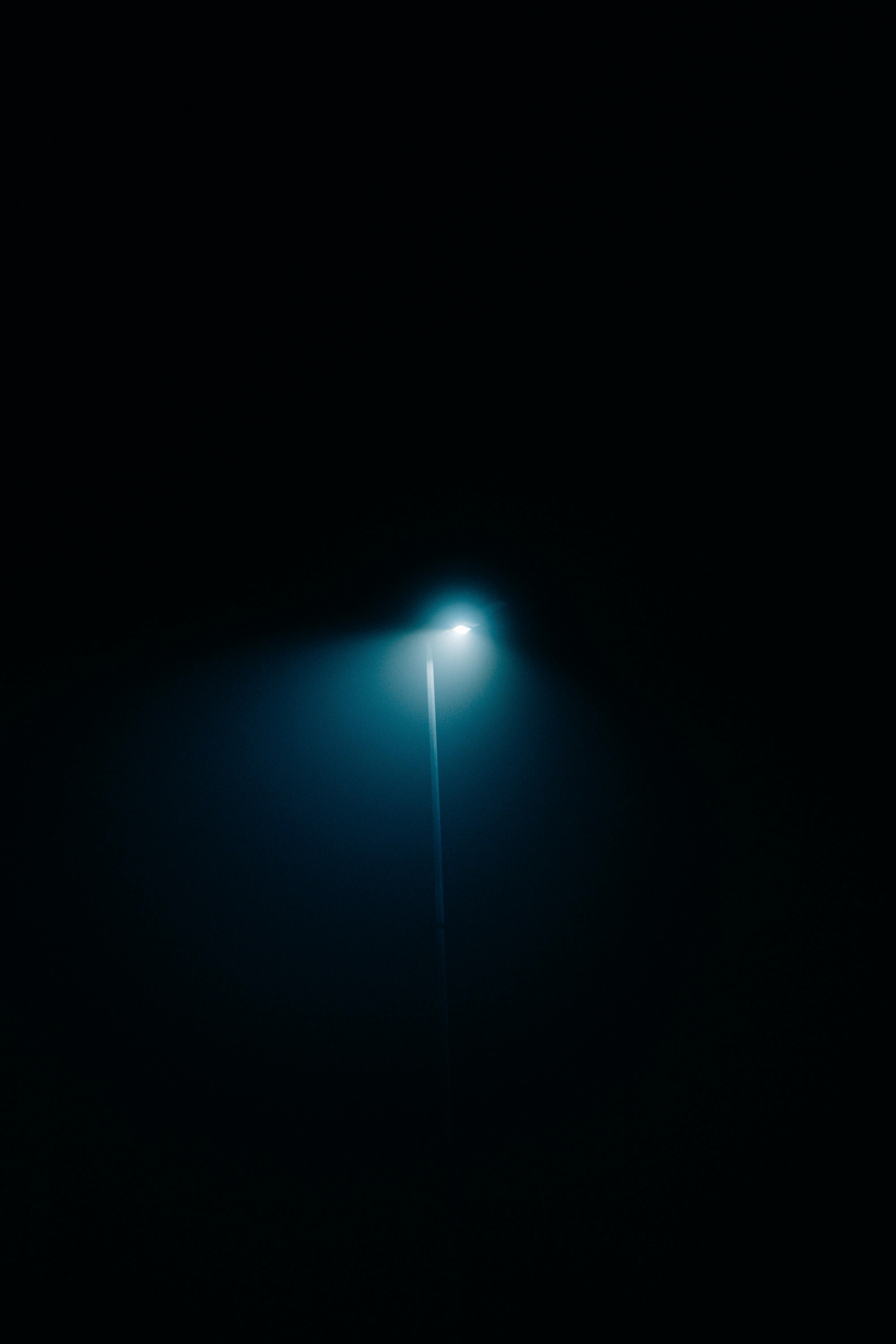 A solitary streetlight casts an ethereal glow in the darkness, creating a sense of mystery.