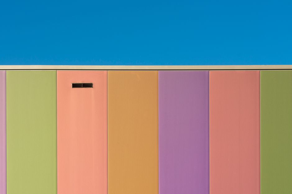 A colorful facade showcasing pastel hues of a modern building against a clear blue sky.