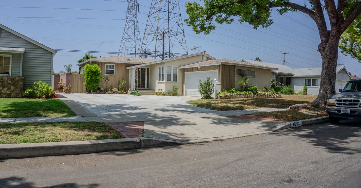 Charming suburban street with mid-century homes and lush greenery on a sunny day.