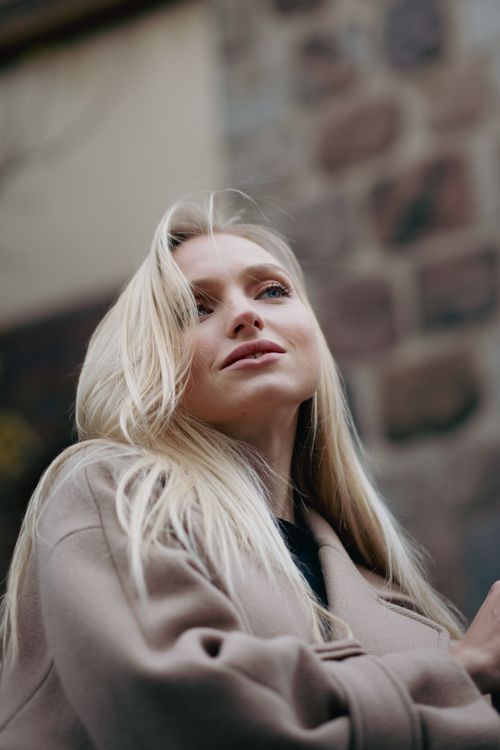Free Portrait of a blonde woman in a coat, exuding fashion and confidence. Stock Photo