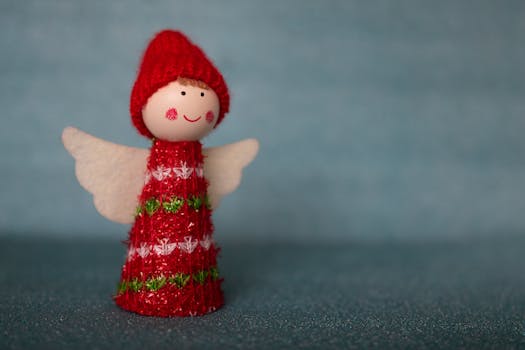 Charming handmade Christmas angel figurine with red and white knitted outfit on a blue background.