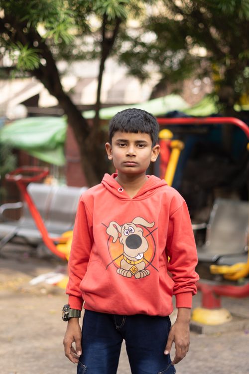 Free Portrait of a boy in a red hoodie standing outdoors in a playground in Jammu. Stock Photo