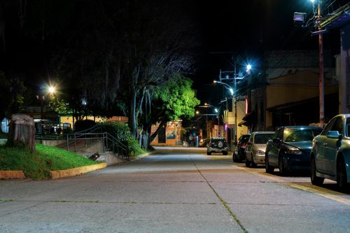 Free A serene nighttime street scene in Mérida, Venezuela, with parked cars and glowing streetlights. Stock Photo
