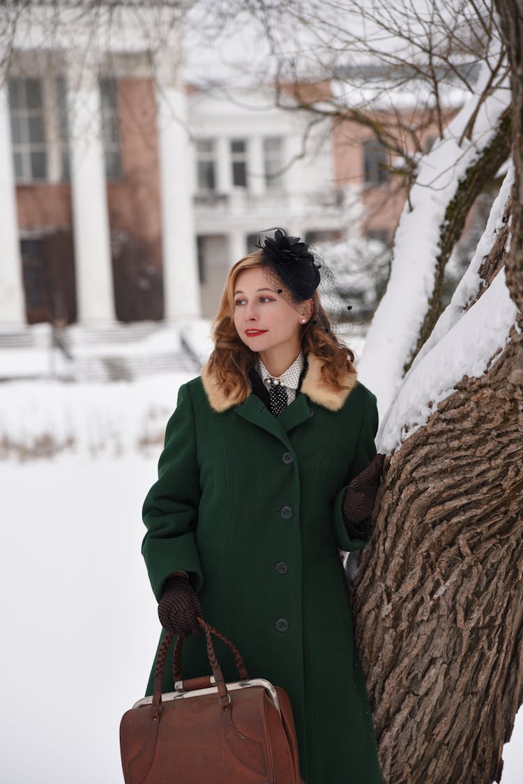 Elegant Woman In A Coat Standing Next To A Tree Outside In Winter 