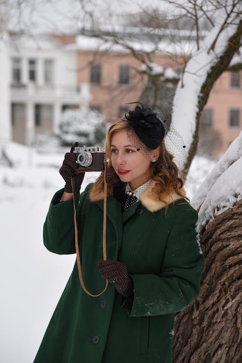 Woman in Green Coat Taking Pictures with Camera