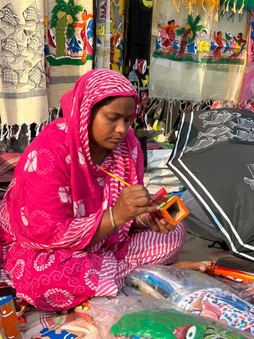 Free A woman artist paints vibrant crafts at a bustling bazaar, showcasing traditional artistry. Stock Photo