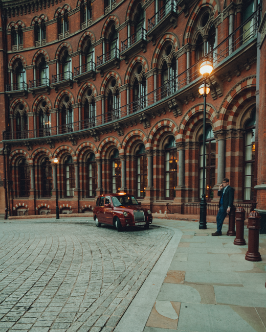 Iconic London architecture with a classic red taxi at St Pancras Renaissance Hotel.