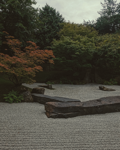 Free Peaceful Japanese garden scene featuring raked gravel and lush greenery. Stock Photo