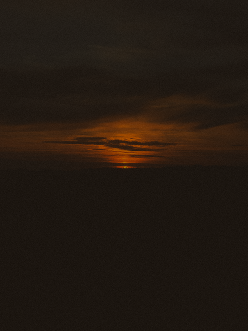 Free A striking sunset with clouds creating a dramatic dark silhouette against the vibrant horizon. Stock Photo