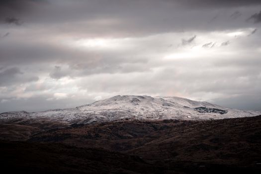 Breathtaking view of snow-covered Elmadağ Mountain in Ankara, Türkiye, under a gloomy sky.
