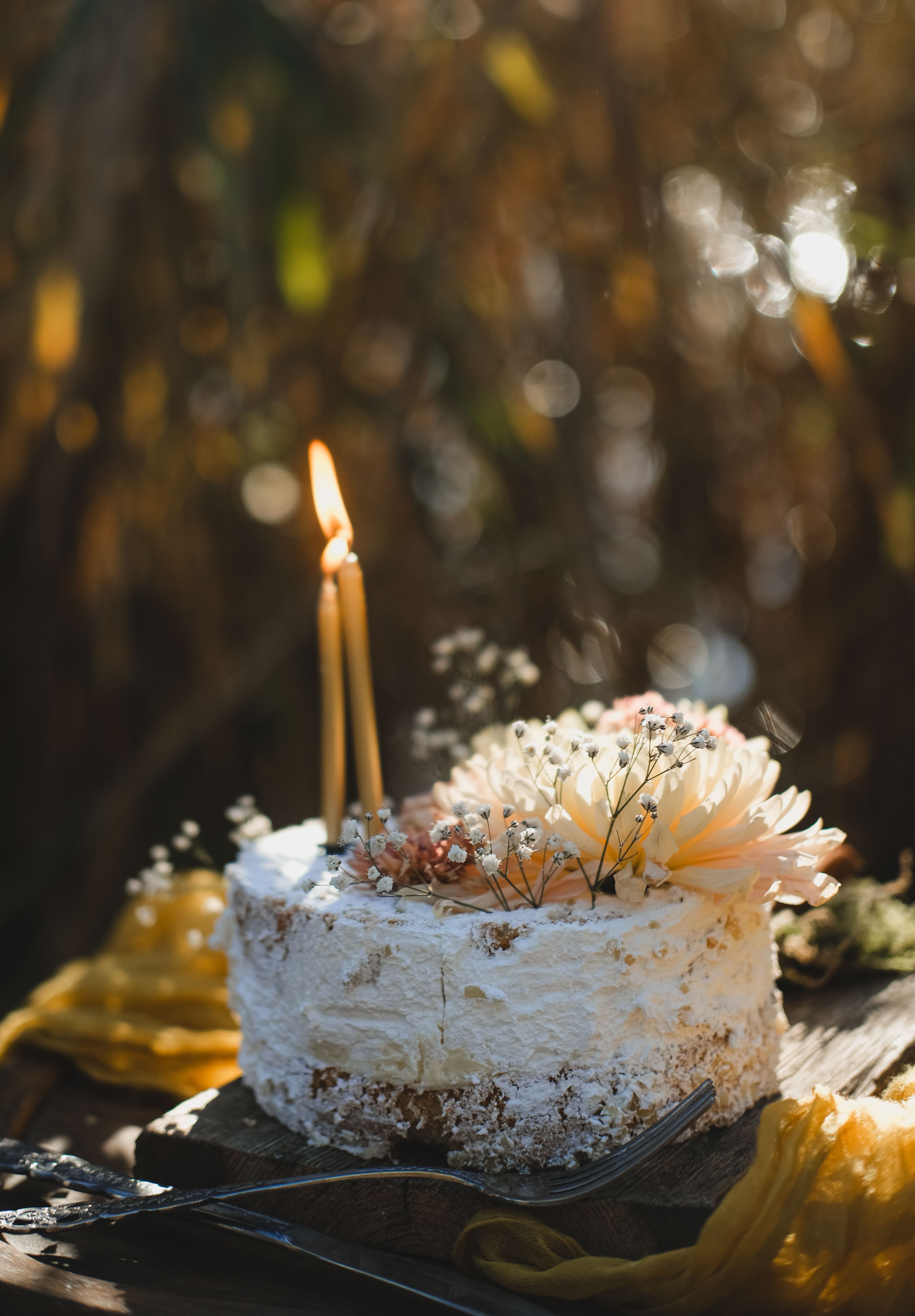 Gâteau d'anniversaire décoré de fleurs et de bougies servi en extérieur dans un jardin