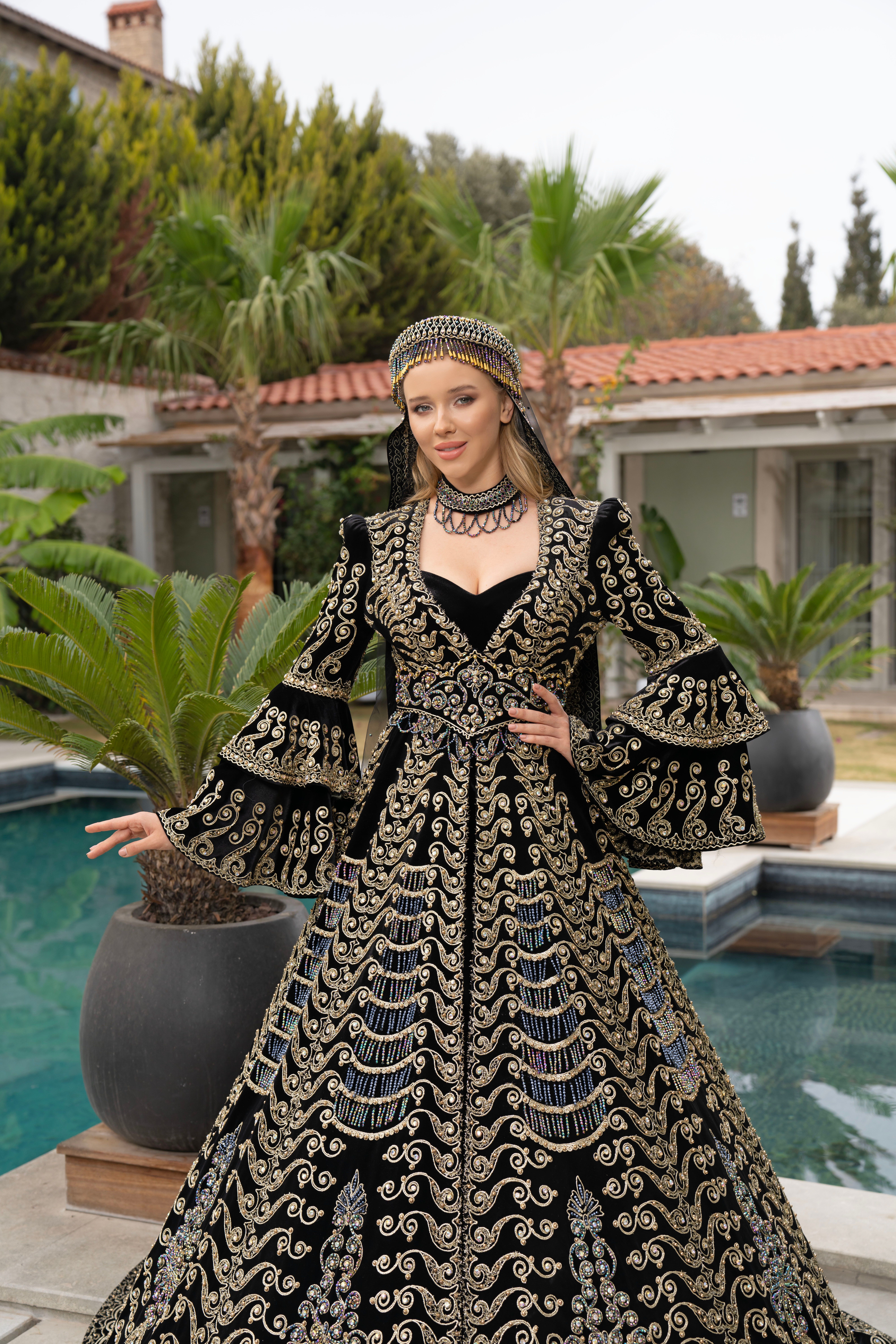 A woman in a luxurious embroidered dress poses beside a pool in İzmir, Türkiye.