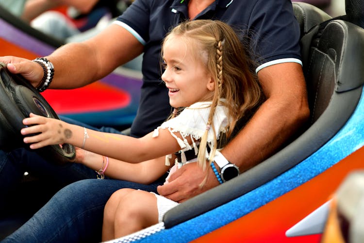 A Little Girl Driving In A Bumper Car With Her Father 