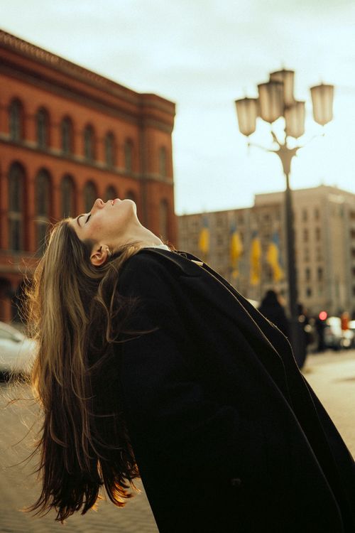 Free Young woman posing in stylish coat on a Berlin street during golden hour. Stock Photo