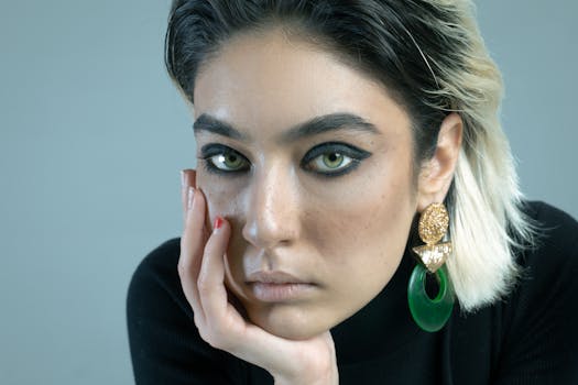 Close-up portrait of a woman with striking green eye makeup and elaborate earrings, captured in a studio in Tehran.