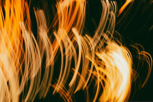 Abstract long exposure photograph of bright orange and yellow light streaks against a dark background.