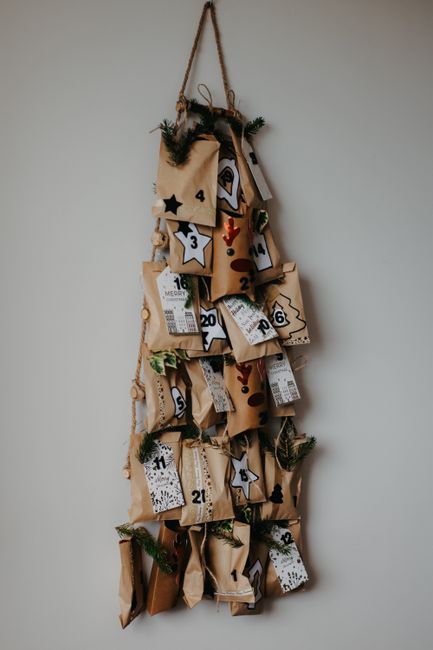 Handmade advent calendar with numbered kraft paper bags and pine decor, perfect for Christmas countdown.