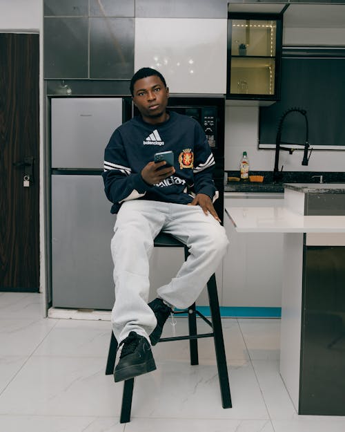 Man Sitting with Smartphone in Kitchen