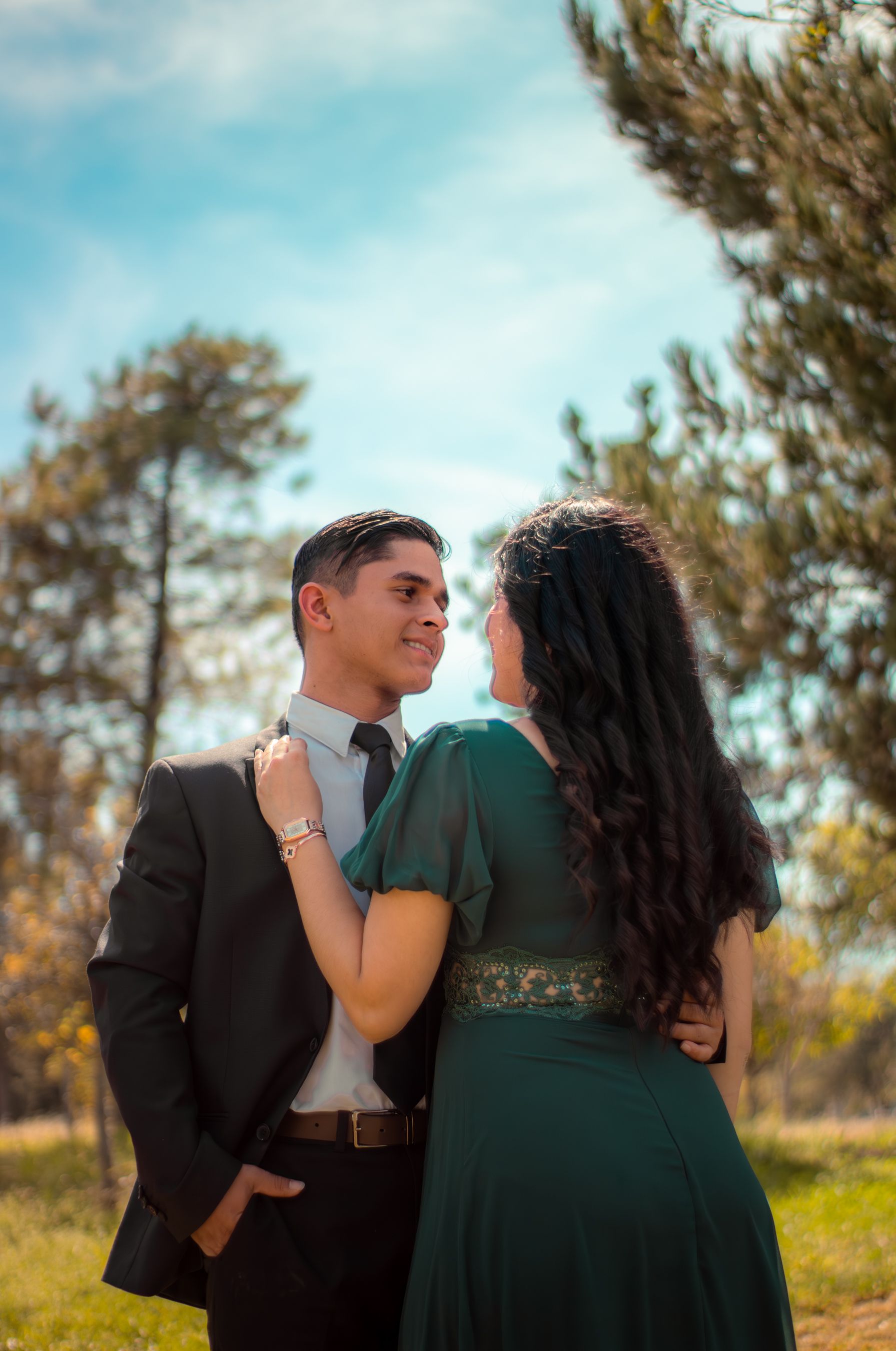 Fotomural Pareja romántica vestida de manera formal abrazándose afuera en un día soleado.