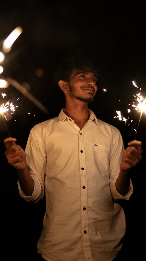 Man Holding Burning Sparklers at Night