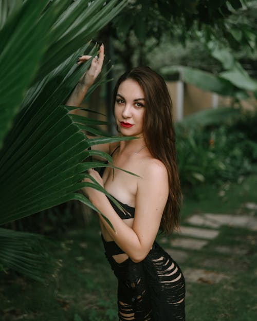Brunette Woman Posing Among Tropical Plants 