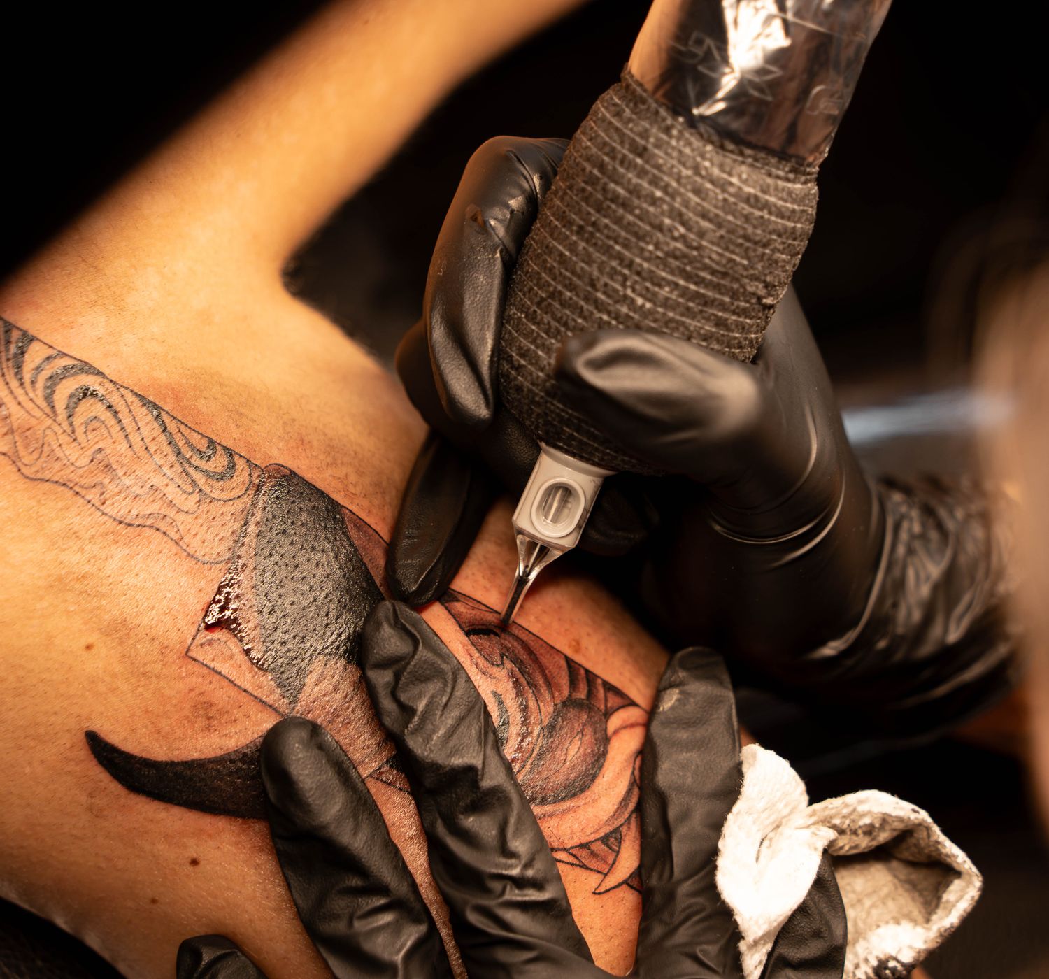 A tattoo artist skillfully working on an intricate design with precision needles.