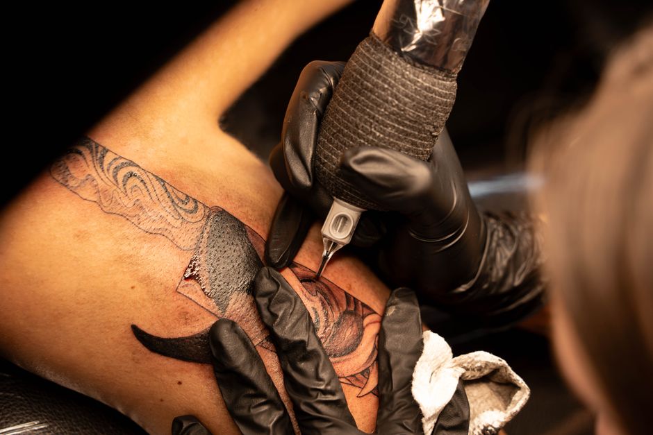 Tattoo apprentice learning cover-up techniques from a Mentor in a tattoo studio Tattoo apprentice learning cover-up techniques from a Mentor in a tattoo studio